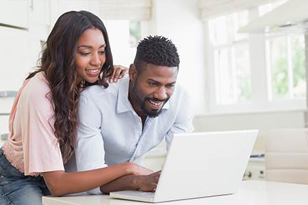 young man and woman looking at laptop at kitchen table looking at online mortage lending tools