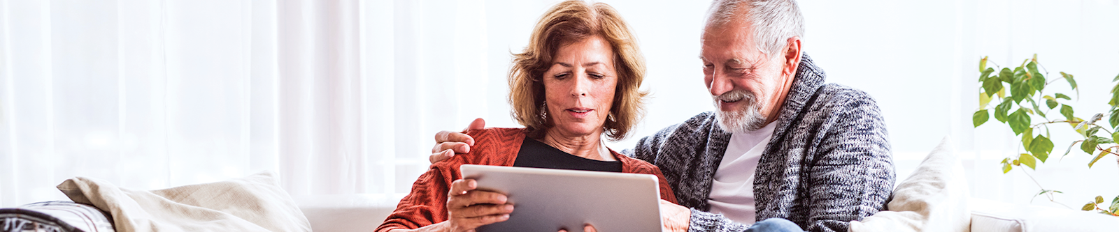 Mature husband and wife looking at IRA account on laptop at home