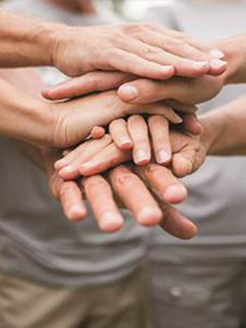 several male and female hands stacked together to represent community