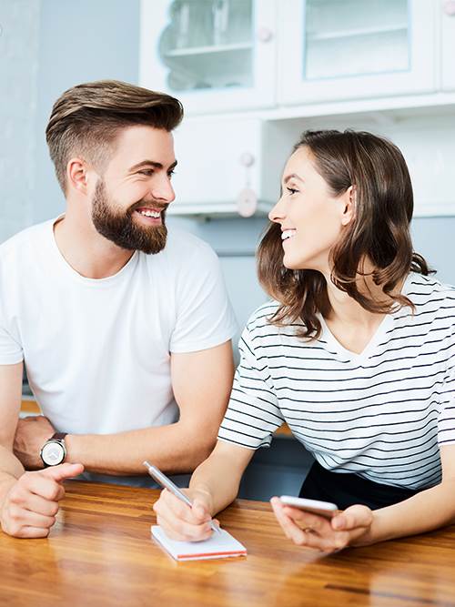 man and woman smiling at each other woman holding mobile device