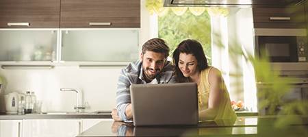man and woman in kitchen on laptop using digital banking securely